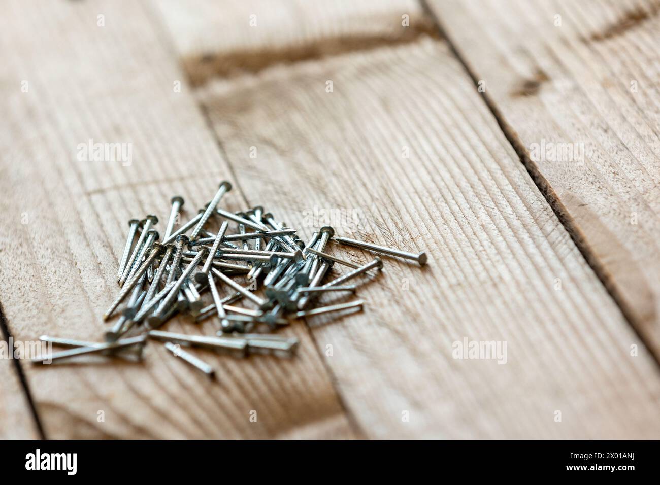 Primo piano di chiodi metallici lucidi per carpenteria su fondo in legno Foto Stock