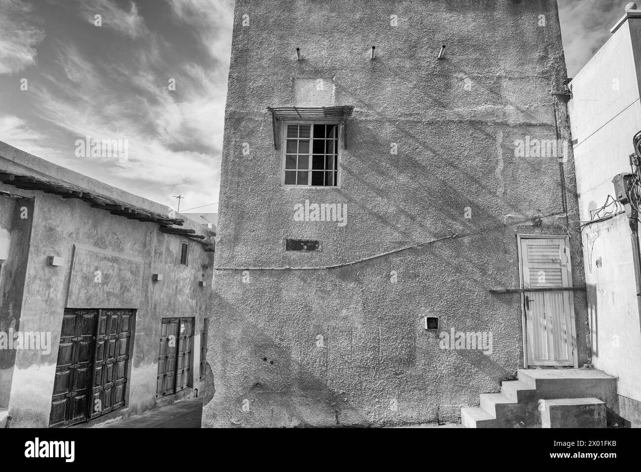 Immagine in bianco e nero di vecchi edifici in una vecchia area urbana di una città mediorientale con porte di legno che si affacciano su negozi chiusi. Foto Stock