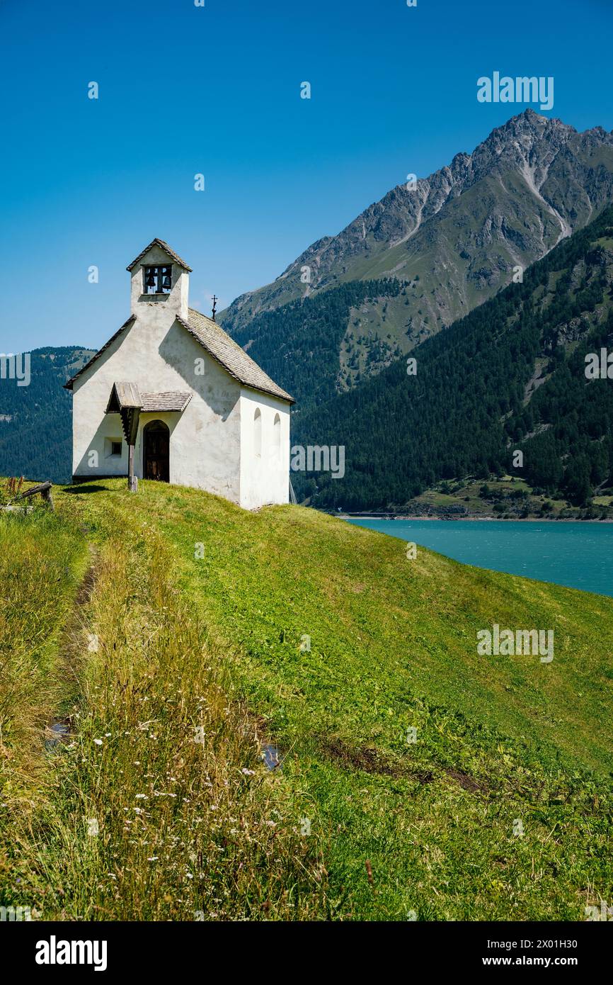 La piccola chiesa bianca sulle rive del lago di Resia in alto Adige Foto Stock