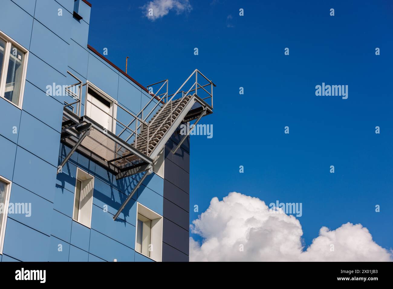 Edificio azzurro con una fuga d'incendio laterale, sotto un cielo con nuvole soffici Foto Stock