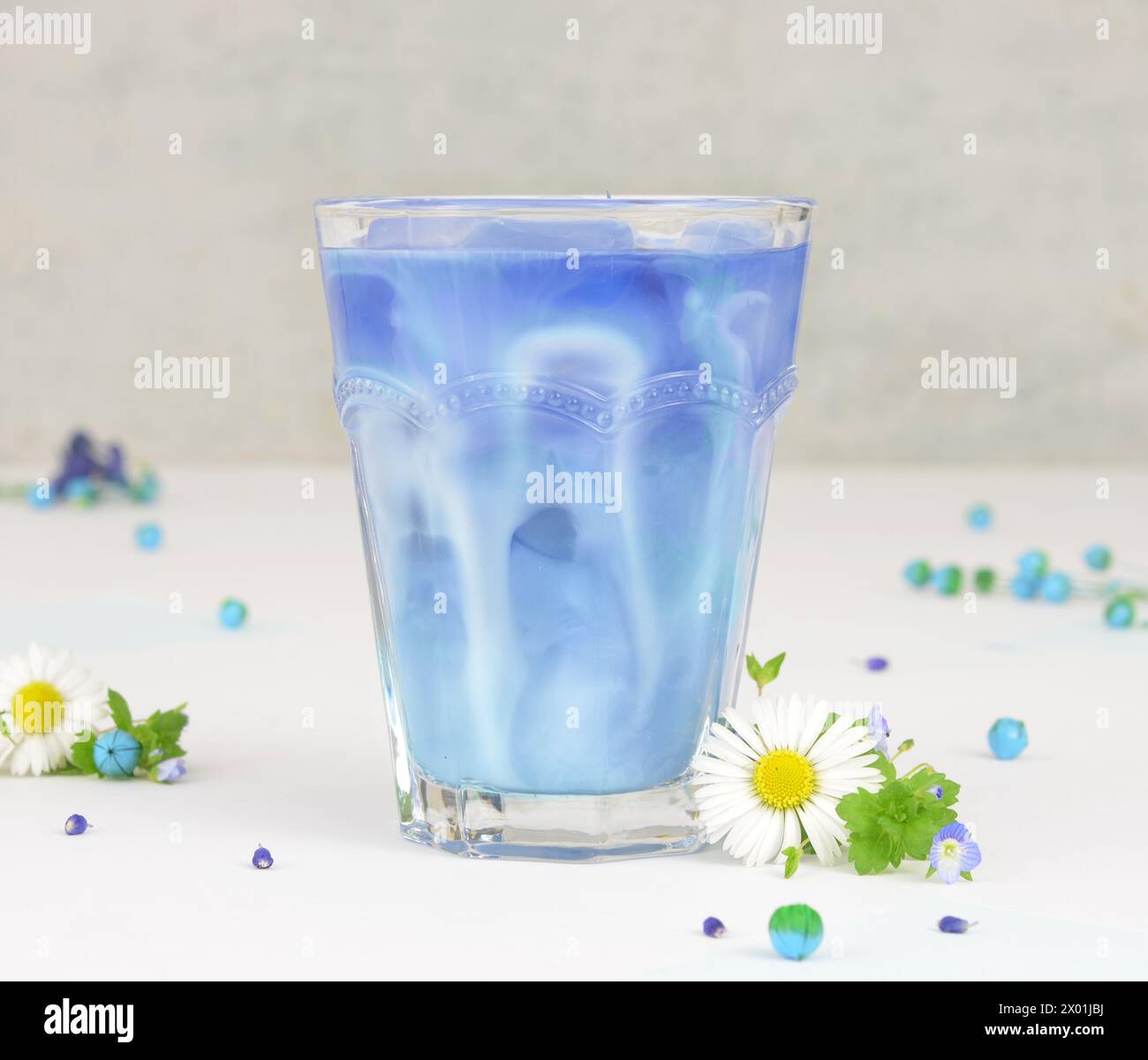 Blue drink with Milk - Butterfly Pea Tea, decorato con margherite e fiori blu. Foto Stock