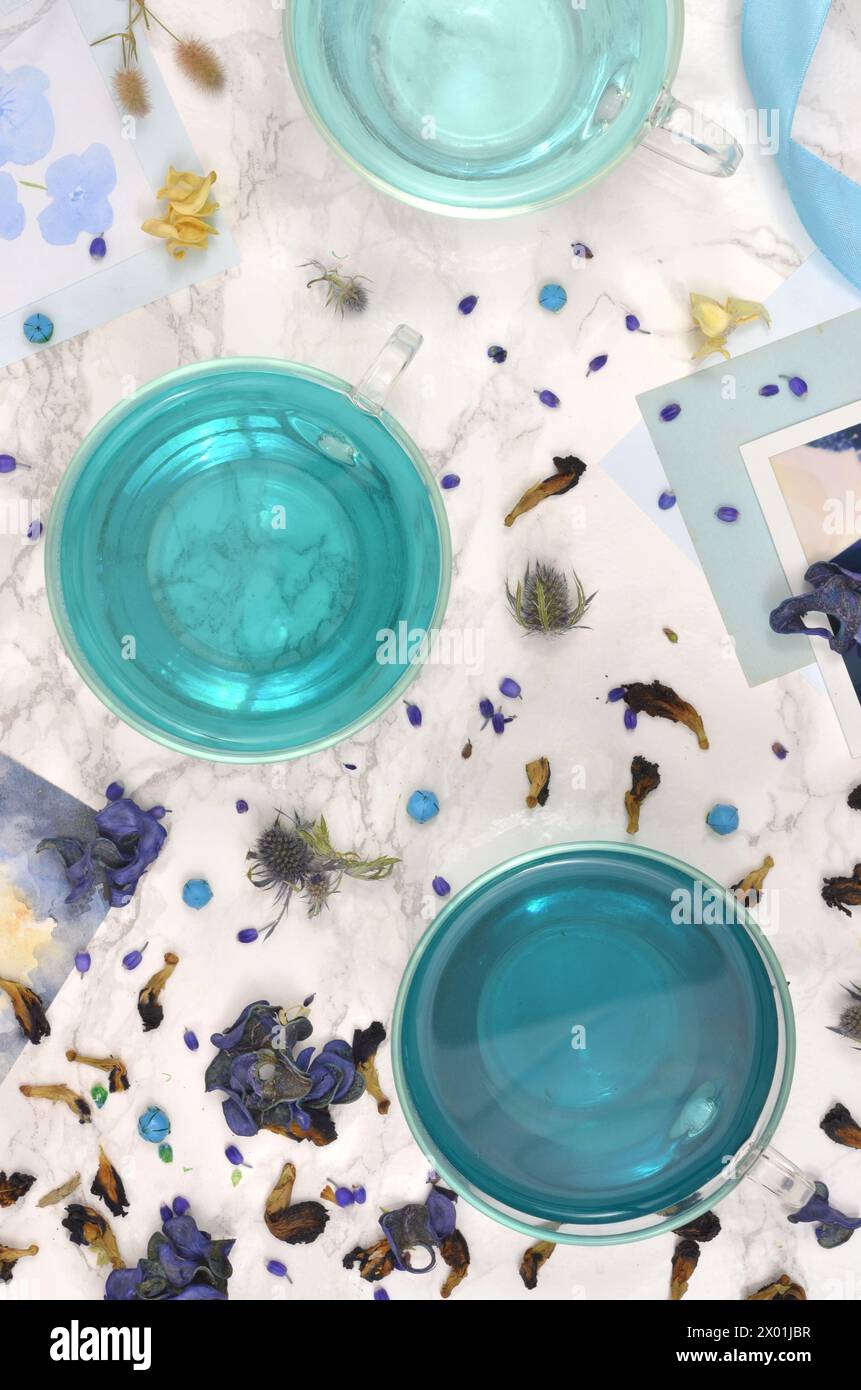 Blue Tea - tè di pisello alle Farfalle, tre tazze di tè blu ed erbe diverse, vista dall'alto. Foto Stock