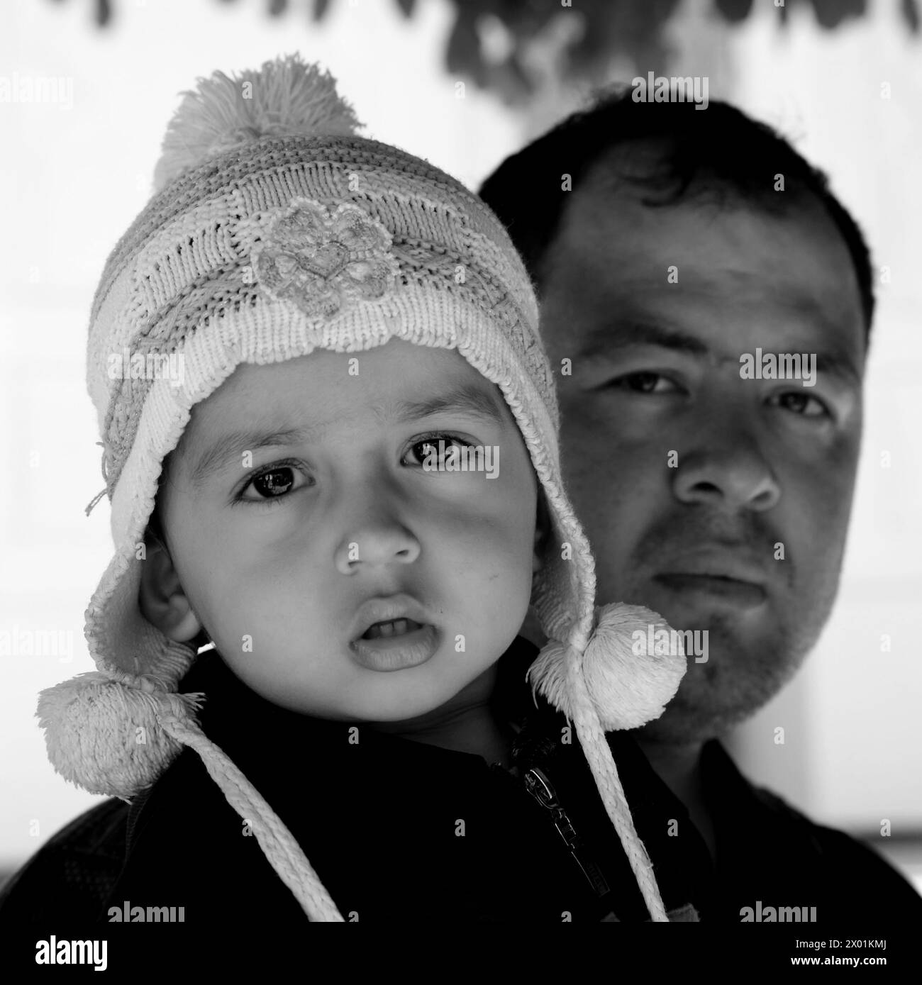 Immagine in bianco e nero di un bambino tenuto da suo padre, Bukhara, Uzbekistan Foto Stock