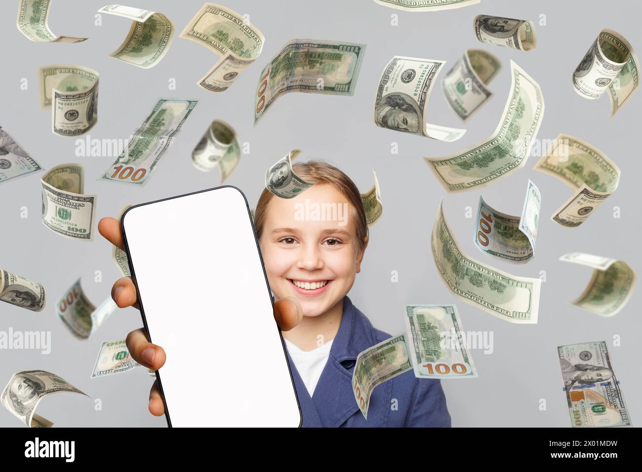 Una bambina carina che si diverte con il display bianco vuoto per smartphone e la caduta di dollari americani in denaro Foto Stock