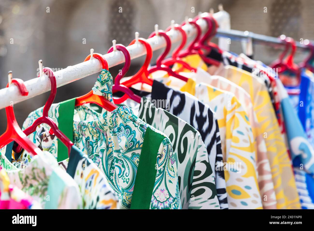 Vesti colorate appendono su scaffali, assortimento di vecchi bazaar Bukhara Foto Stock