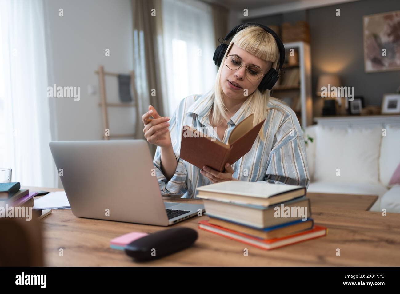 Giovane studentessa universitaria, donna universitaria o ragazza, studia per l'esame finale a casa. Le giovani donne imparano e si educano usando libri e computer portatili Foto Stock