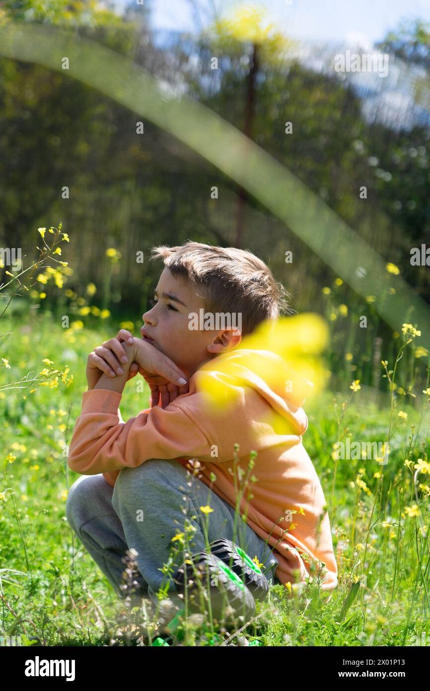 Bambino premuroso nella natura in primavera con fiori gialli Foto Stock