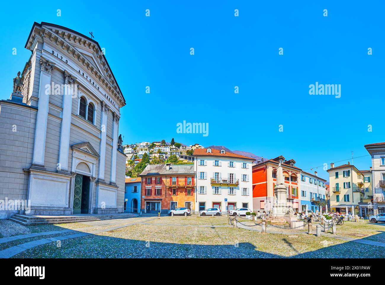 Storica Piazza Sant'Antonio con la Chiesa di Sant'Antonio, una serie di densa case a schiera e il versante alpino sullo sfondo, Locarno, Ticino, Svizzera Foto Stock