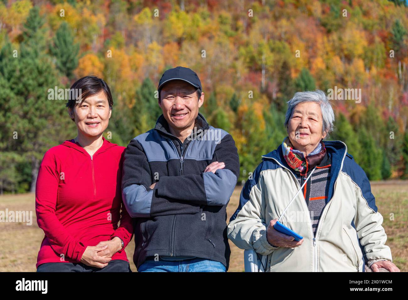 Donna anziana e famiglia in posa per le foto in un parco con colori autunnali sullo sfondo. Mont Tremblant. Québec. Canada. Foto Stock