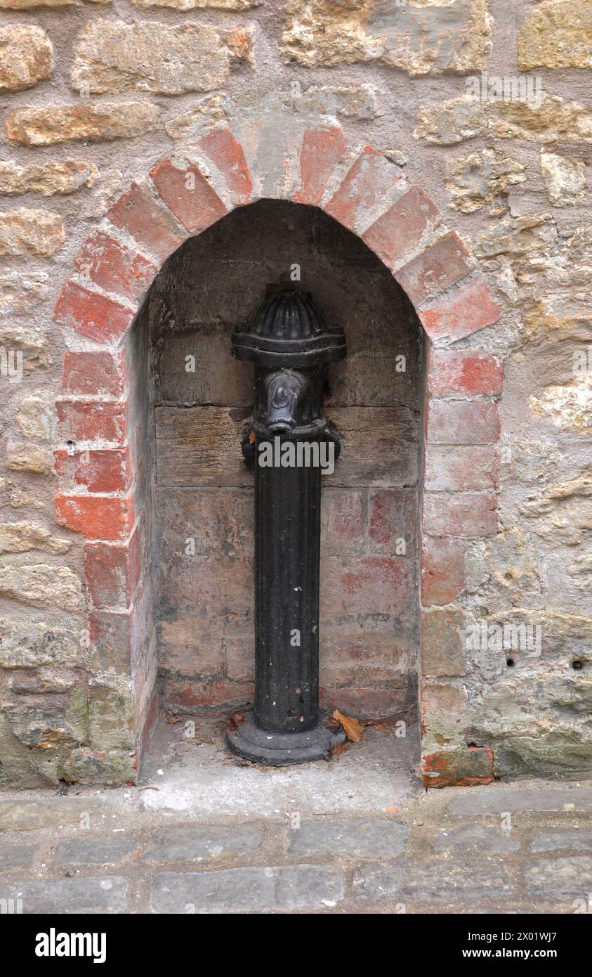 Vecchio tubo dell'acqua in ghisa in un'alcova incastonata nel muro di un vecchio cottage di tessitori a Sheppards Barton, nella storica città di Frome, nel Somerset. Foto Stock