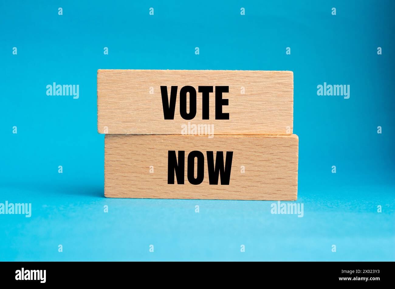 Vota ora parole scritte su blocchi di legno con sfondo blu. Simbolo del voto concettuale. Copia spazio. Foto Stock