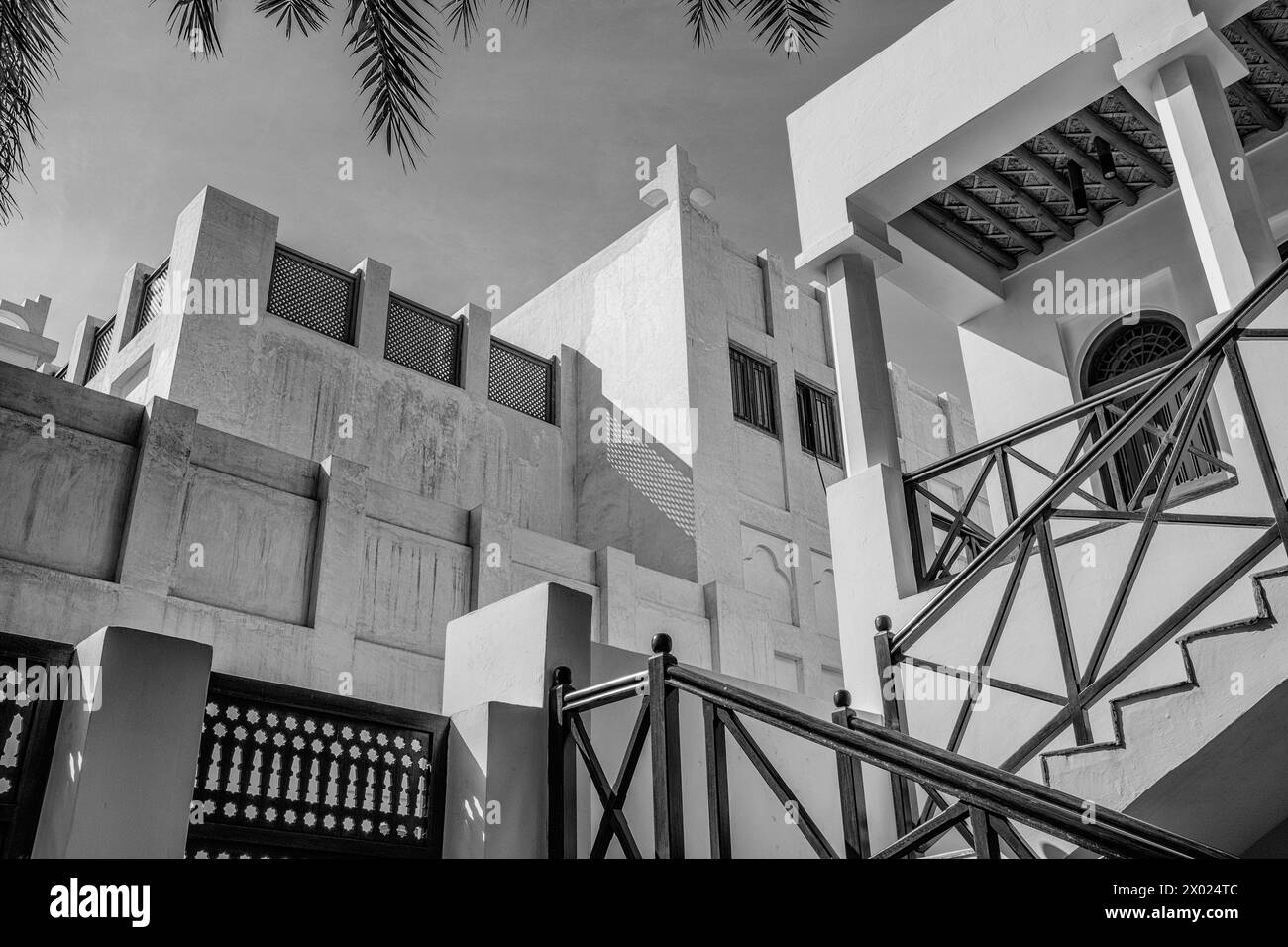 Un'immagine monocromatica e filtrata di edifici in un'area storica mediorientale di case arabe tradizionali restaurate con finestre con persiane e PL bianco Foto Stock