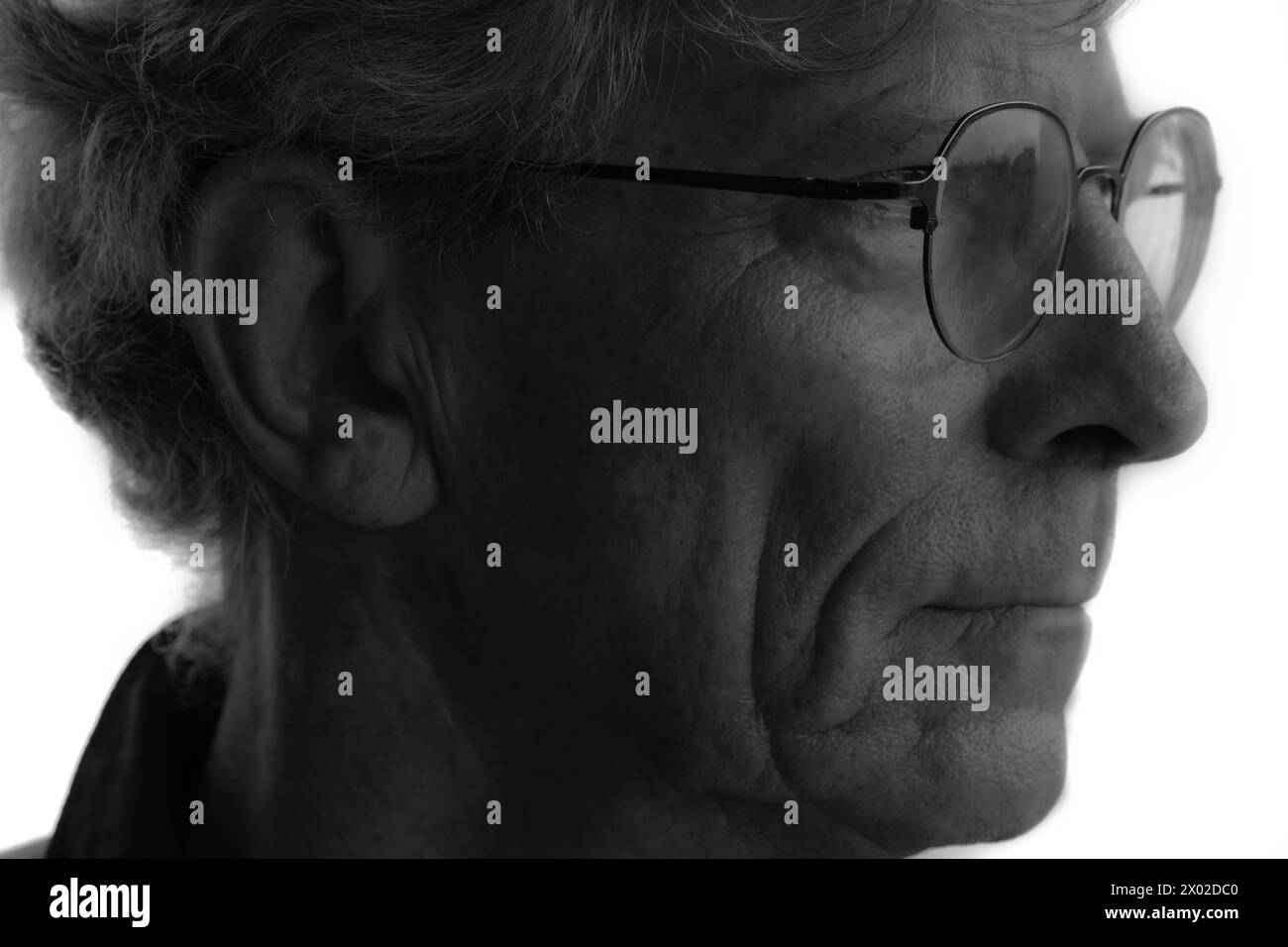 Un ritratto a basso contrasto di un vecchio con gli occhiali Foto Stock