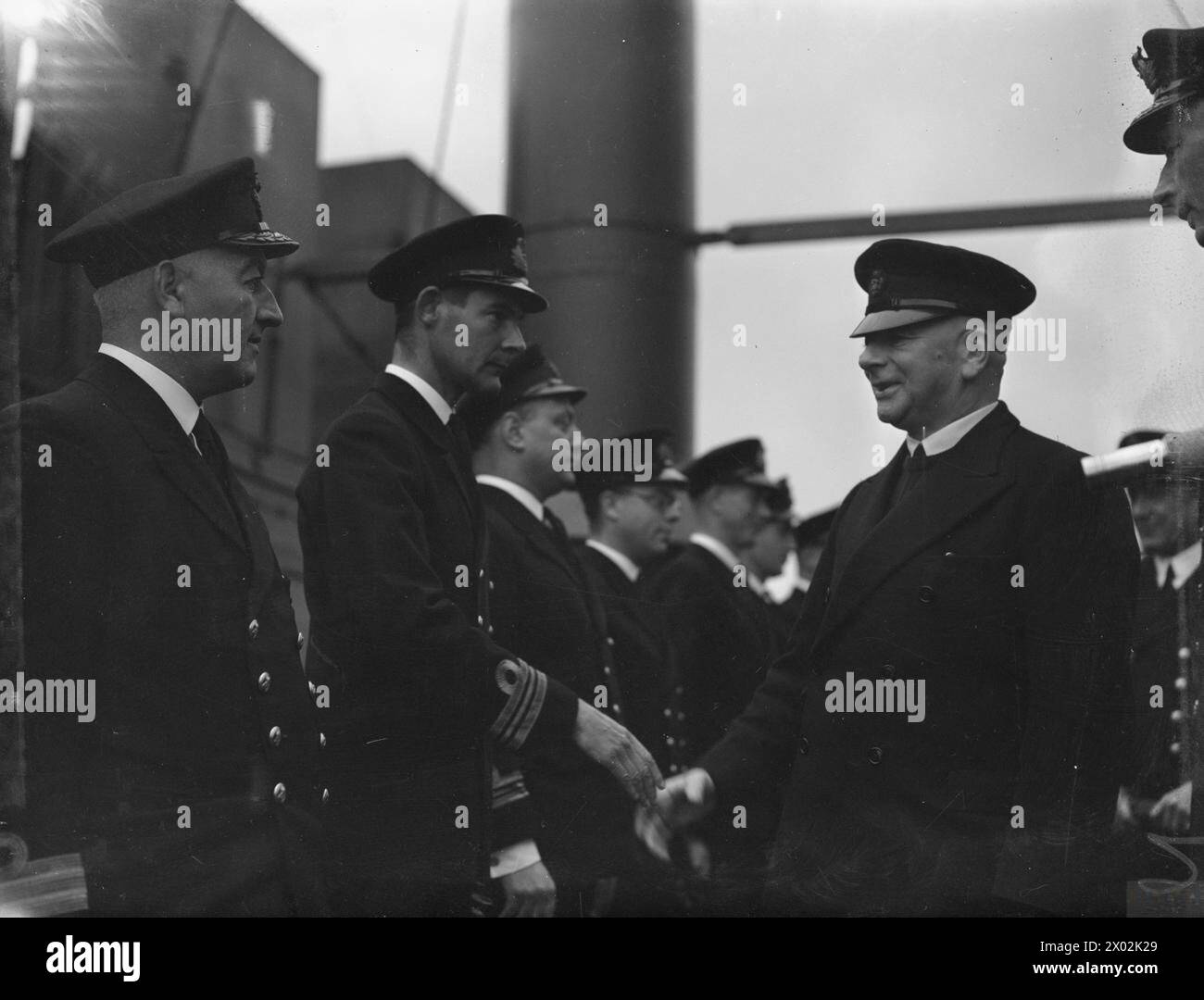 Il 6 luglio 1942, il primo Lord dell'Ammiragliato visitò una nave deposito sottomarino, stringendo la mano agli ufficiali a bordo, evidenziando la supervisione e l'interazione con il personale della Royal Navy. Foto Stock