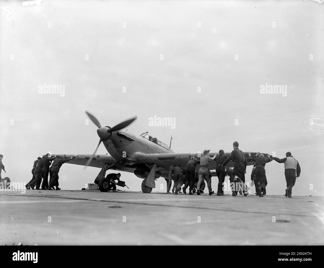 Il 15-17 agosto 1943 al largo di Lamlash, la HMS Argus celebra 25 anni di servizio durante l'addestramento dei piloti della Fleet Air Arm. Le squadre di movimentazione degli aeromobili gestiscono un Hawker Hurricane dopo l'atterraggio. Foto Stock