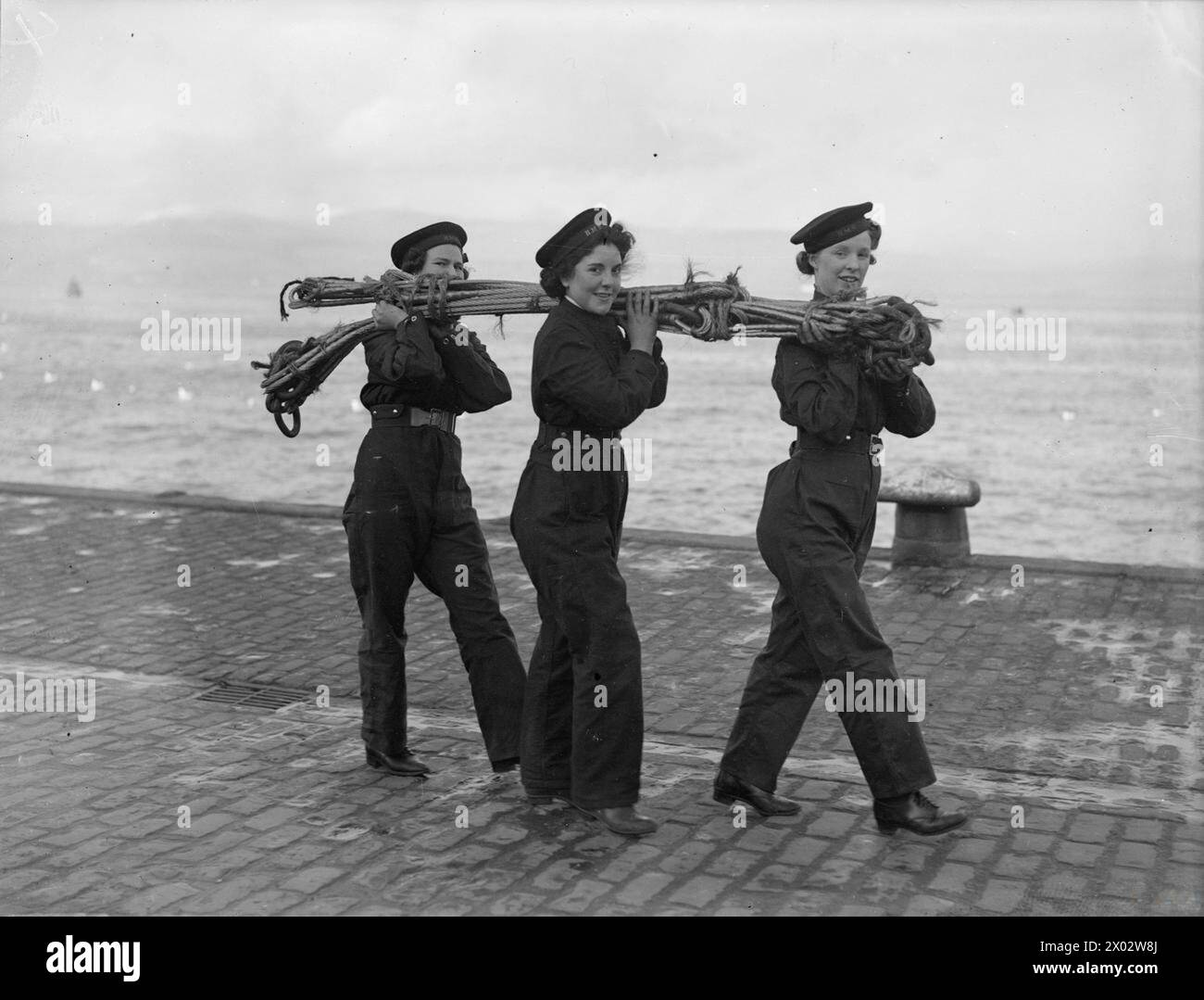 LE CHIAVI ORA AFFRONTANO I LAVORI DI MANUTENZIONE. 11 MARZO 1943, GREENOCK, UN NUMERO SEMPRE CRESCENTE DI LAVORI IMPORTANTI PRECEDENTEMENTE SVOLTI DA UOMINI DELLA ROYAL NAVY SONO ORA SVOLTI DA MEMBRI DELLA W R N S. A GREENOCK PER ESEMPIO ORA SONO IMPIEGATI IN LAVORI DI MANUTENZIONE. - Le strozzature dei fili vengono trasportate dall'officina dopo la riparazione Foto Stock