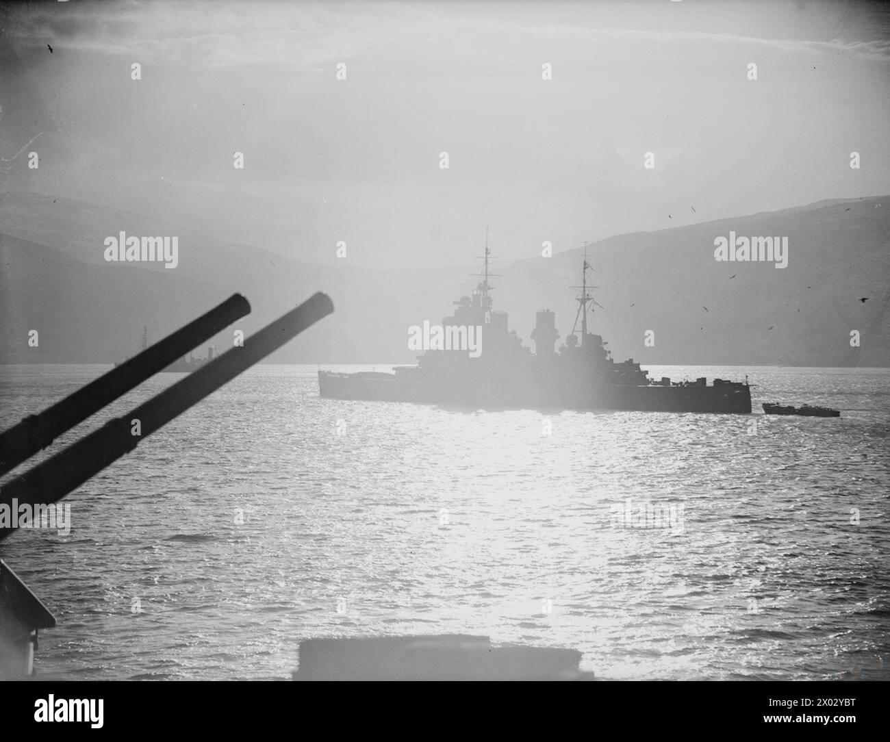 Tra il 15 e il 18 febbraio 1942, la HMS Victorious operò a Hvalfjord e in mare conducendo routine portuali ed esercitazioni di volo. HMS King George V è raffigurato all'ancora al sole. Foto Stock