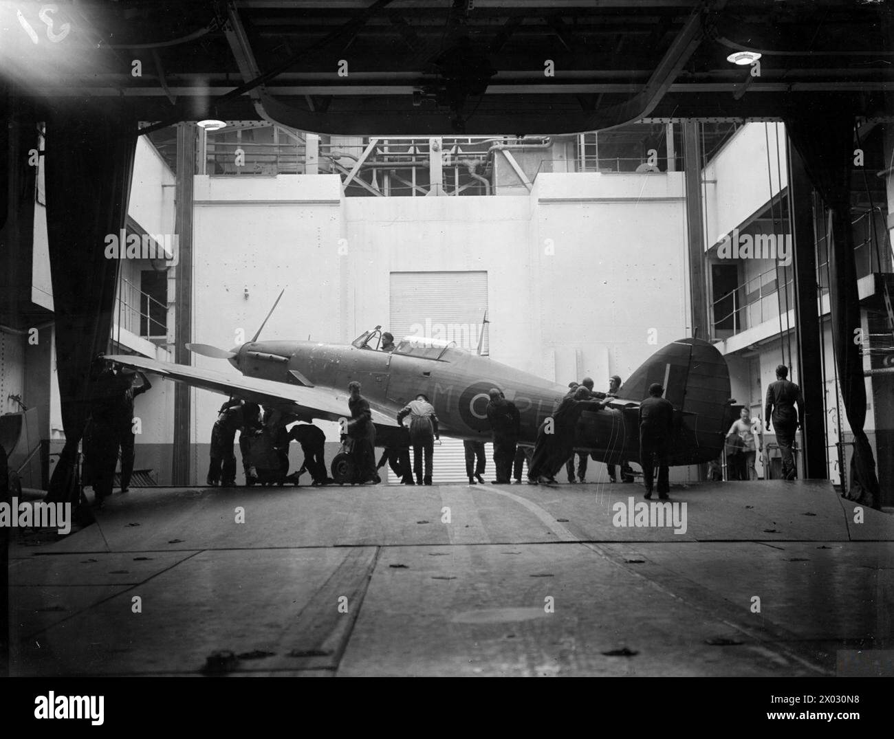 La HMS Argus al largo di Lamlash il 15-17 agosto 1943 allena i piloti della Fleet Air Arm sugli sbarchi di portaerei, segnando 25 anni di servizio continuo. Gli aerei vengono sollevati dall'hangar al ponte di volo. Foto Stock