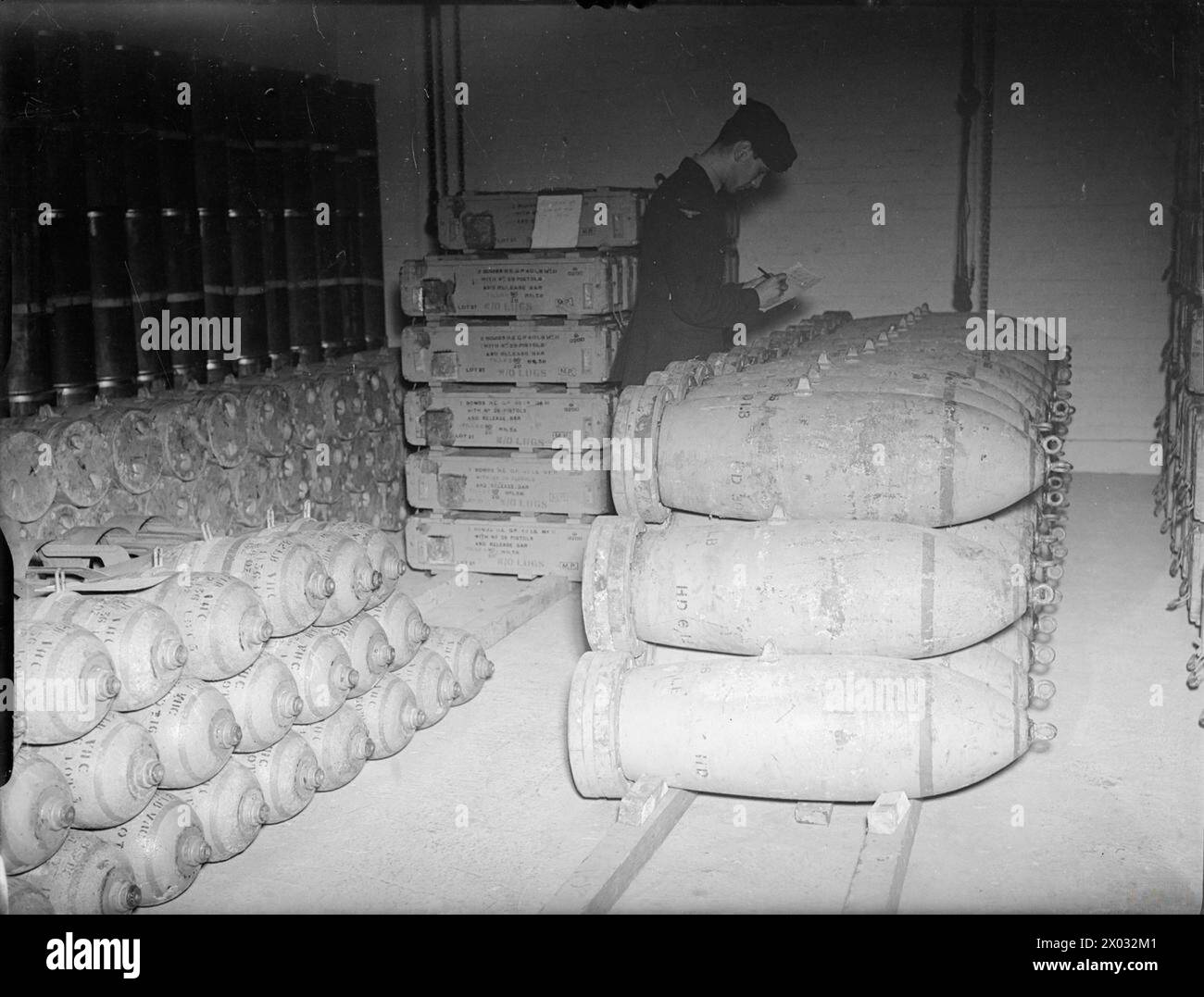 Un aviere della RAF ispeziona bombe per uso generale da 500 lb nei depositi di bombe della No. 10 Operational Training Unit, Abingdon, Berkshire, 1939-1941, sotto le operazioni del Bomber Command. Foto Stock