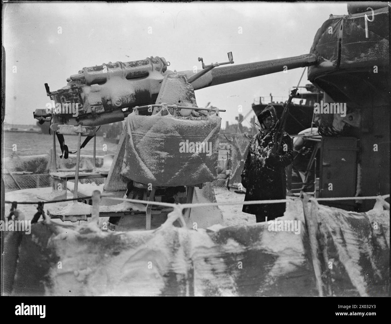 LA ROYAL NAVY DURANTE LA SECONDA GUERRA MONDIALE - il cacciatorpediniere, HMS ESKIMO, presentò un aspetto completamente bianco dopo una grave tempesta di neve. Una sentinella si trova accanto a un Mark Vgun innevato da 4 pollici su Mark III ha montato sul ponte Royal Navy, ESKIMO (HMS) Foto Stock