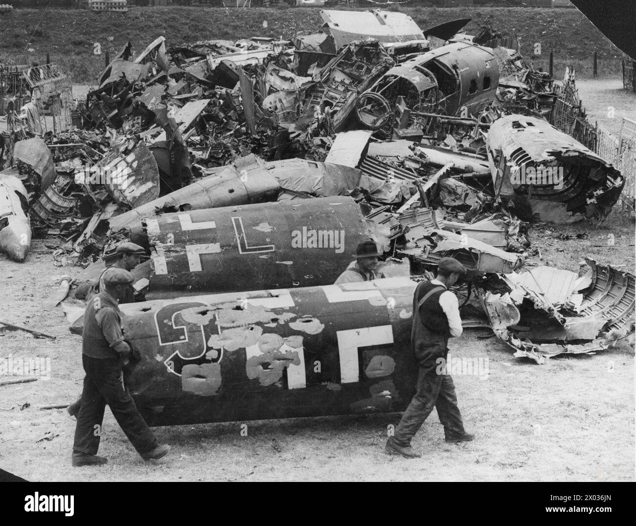 Gli operai spostano una fusoliera danneggiata di un Dornier Do 17 insieme ad altri aerei tedeschi schiantati in un deposito di rottami in Gran Bretagna durante la Battaglia d'Inghilterra, nell'agosto 1940. Foto Stock