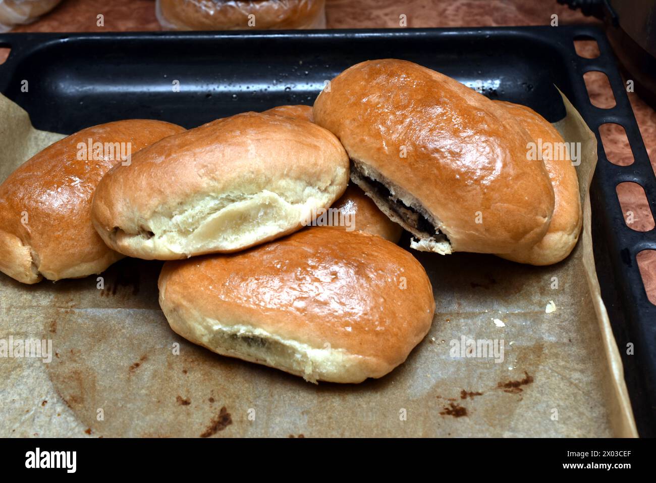 Ci sono torte con semi di papavero ripieni all'interno in un cumulo su una teglia da forno. Foto Stock