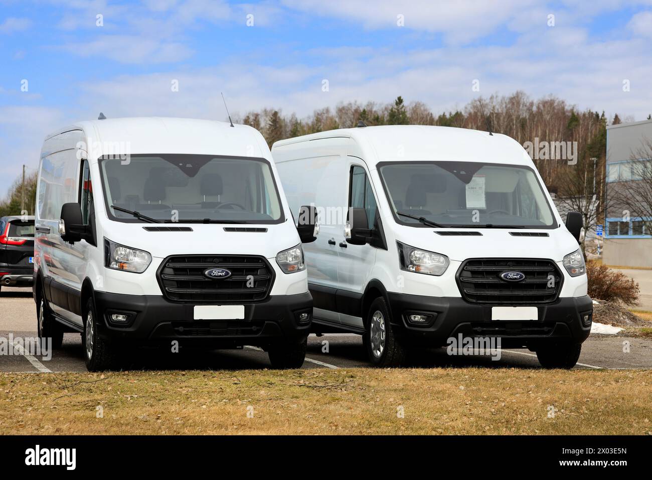 Due nuovi furgoni bianchi Ford Transit EcoBlue Hybrid parcheggiati all'esterno presso una concessionaria. Salo, Finlandia. 31 marzo 2024. Foto Stock