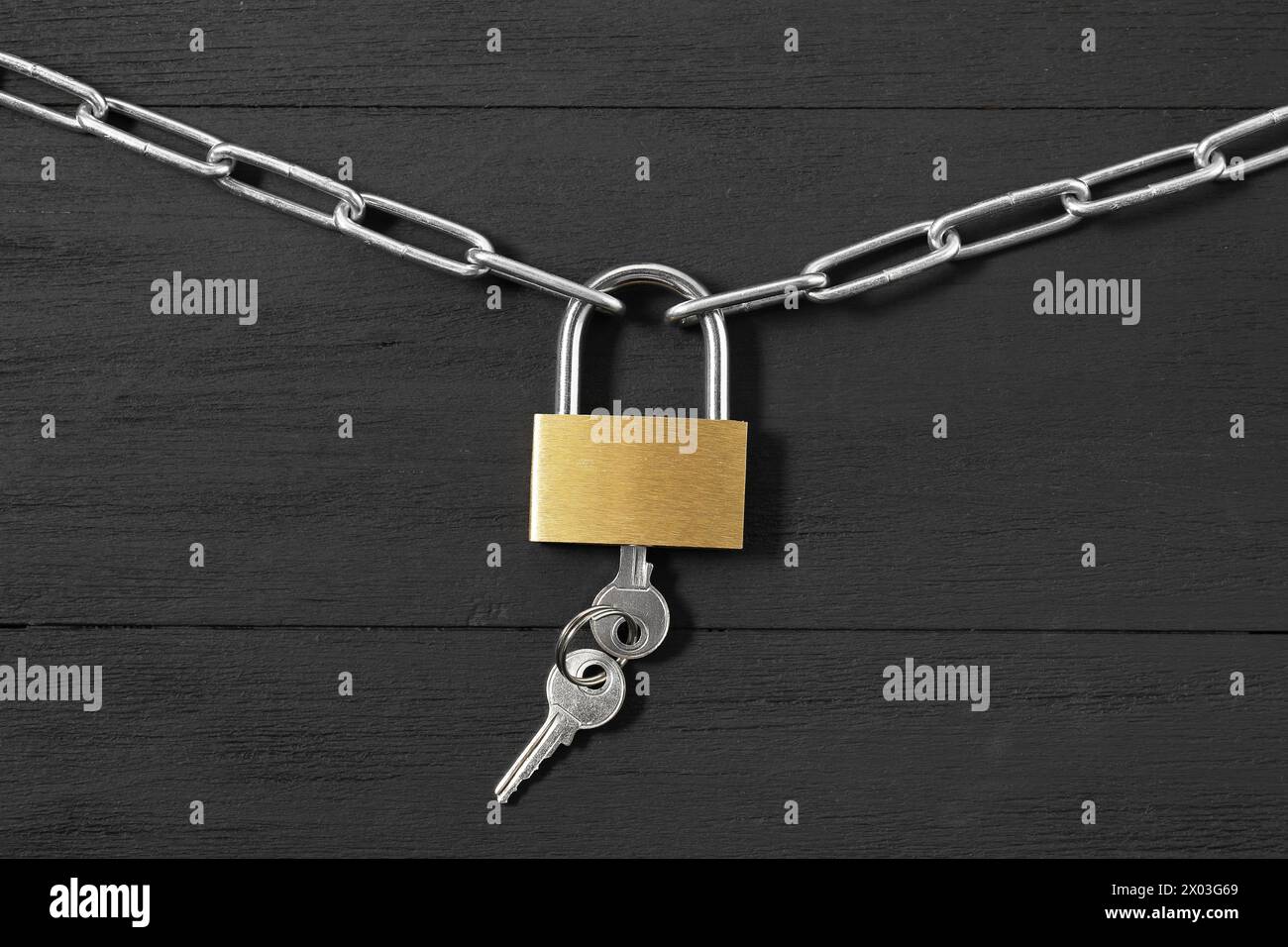 Lucchetto in acciaio con chiavi e catena su tavolo in legno nero, vista dall'alto Foto Stock