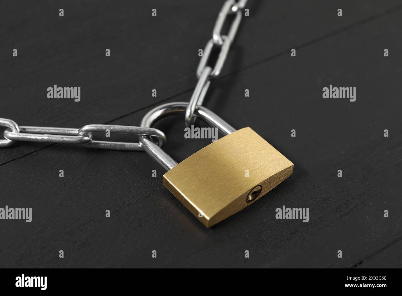 Lucchetto in acciaio con catena su tavolo in legno nero, primo piano Foto Stock