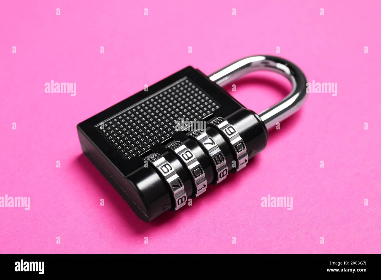 Un lucchetto combinato in acciaio su sfondo rosa, primo piano Foto Stock