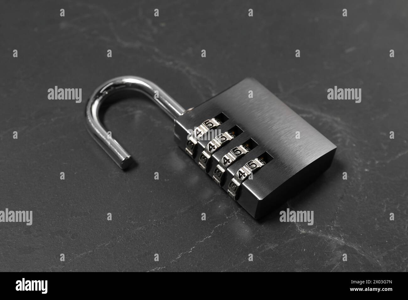 Un lucchetto combinato in acciaio sul tavolo nero, primo piano Foto Stock