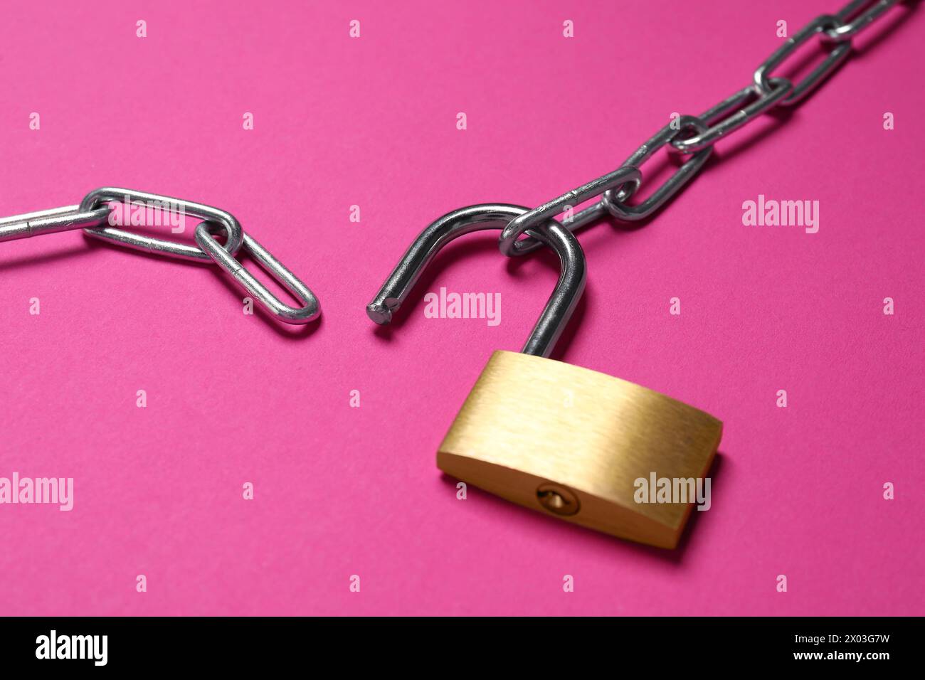 Lucchetto e catena in acciaio su sfondo rosa, primo piano Foto Stock