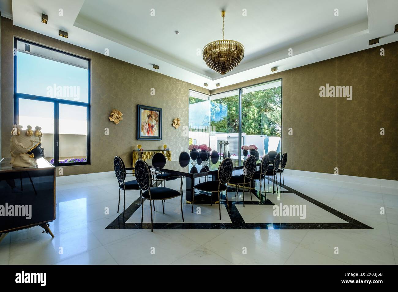 HAMALA, BAHRAIN - 2 MARZO 2019: Elegante sala da pranzo con pavimento in marmo e lampadario in vetro, lungo tavolo da pranzo in marmo e grandi finestre panoramiche in una Foto Stock