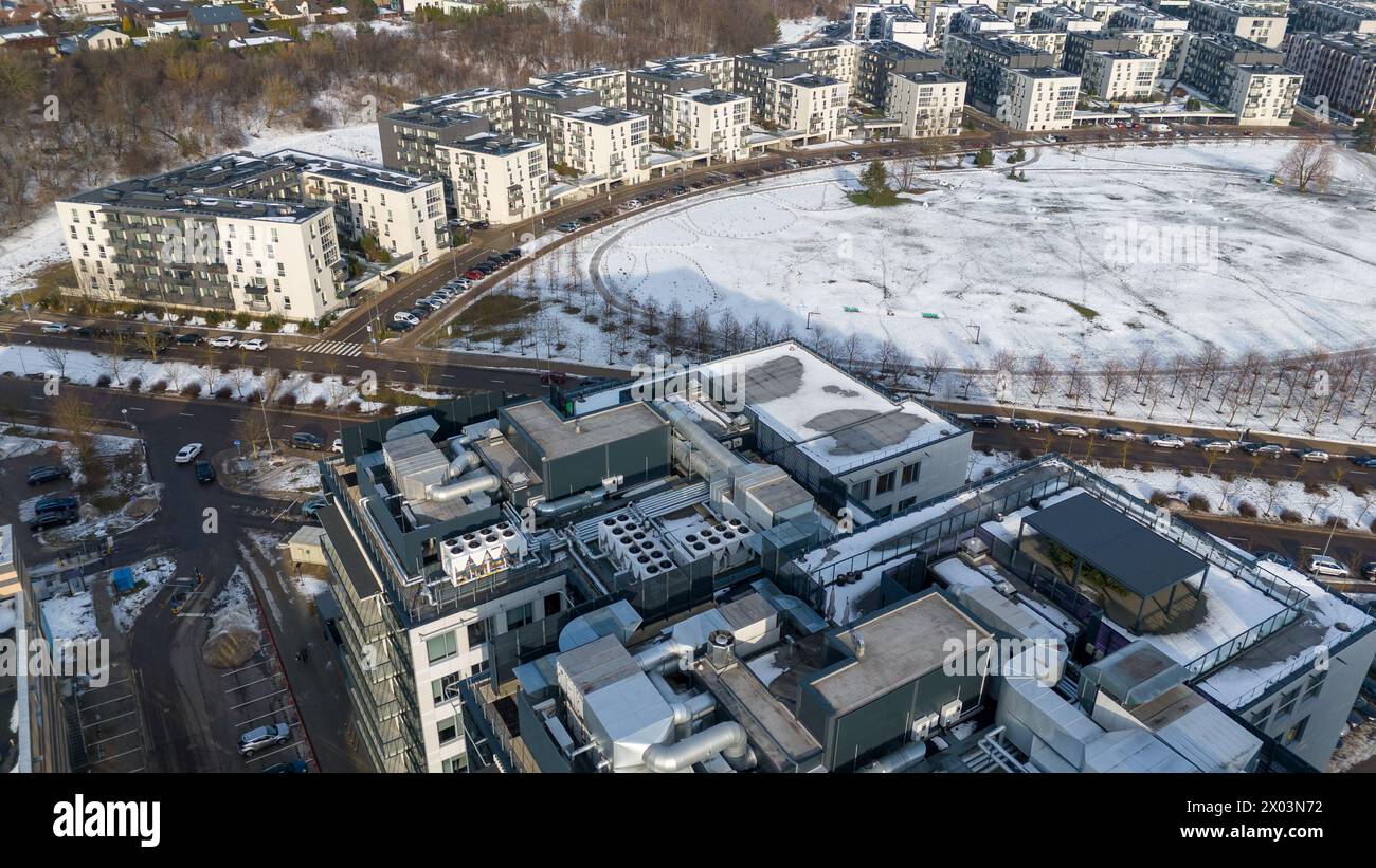 Fotografie con droni di edifici a più piani, grande parco pubblico e grande condizionatore d'aria su un tetto durante le soleggiate giornate invernali Foto Stock