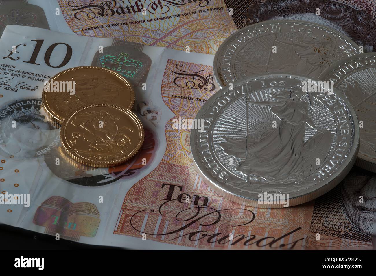 Semisovrani d'oro, monete d'argento della Brittania e banconote da 10 sterline Foto Stock