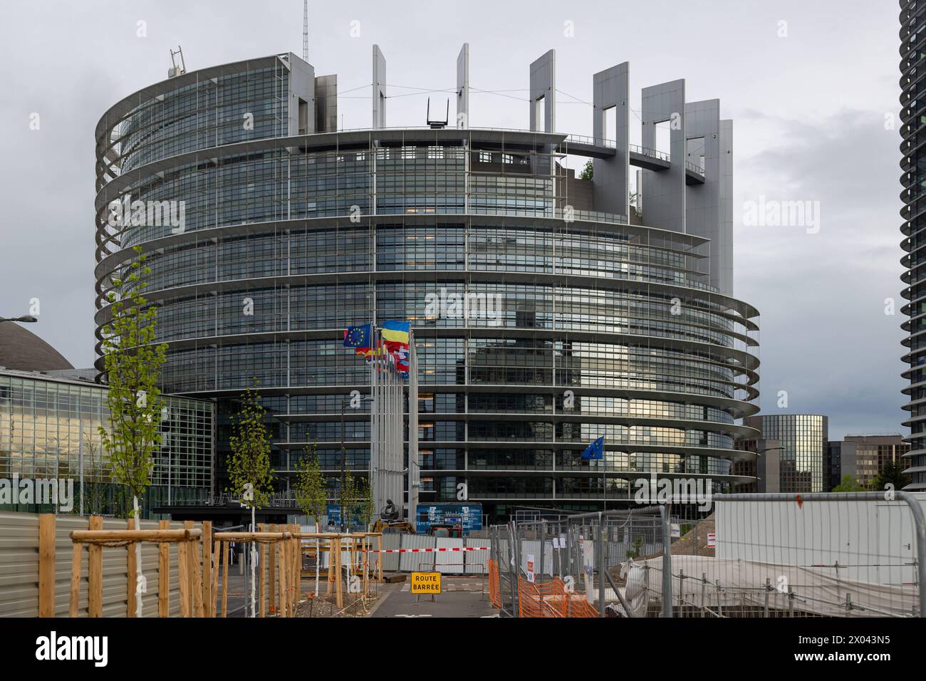 Europäische Parlament Straßburg in der aktuellen Sitzungswoche vor der Europawahl 2024 in Straßburg schmückt die Flagge der Ukraine neben den Europäischen Mitgliedsstaaten und der Europaflagge das Parlamentsgebäude. Eine Baustelle verhindert den Einfachen Zugang zum EU-Parlamentsgebäude. Straßburg Europäische Parlament Bas-Rhin Frankreich *** Parlamento europeo Strasburgo nella settimana di sessione in corso in vista delle elezioni europee del 2024 a Strasburgo, la bandiera dell'Ucraina adorna l'edificio del parlamento accanto agli stati membri europei e la bandiera europea Un cantiere impedisce facile Foto Stock