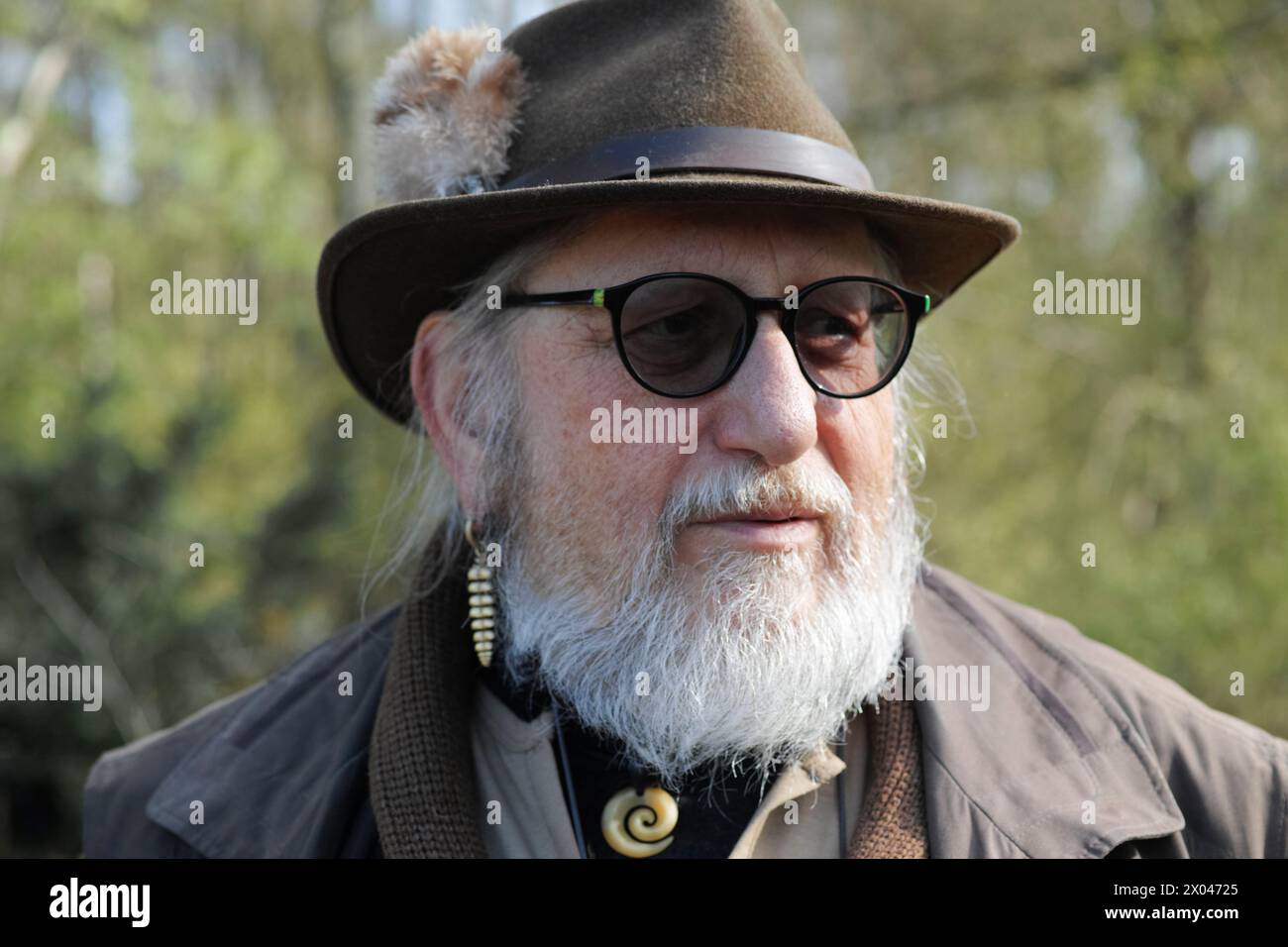 Anziano tedesco di settant'anni con occhiali da sole, barba e cappello verde, una fedora con un piccolo Gamsbart Foto Stock