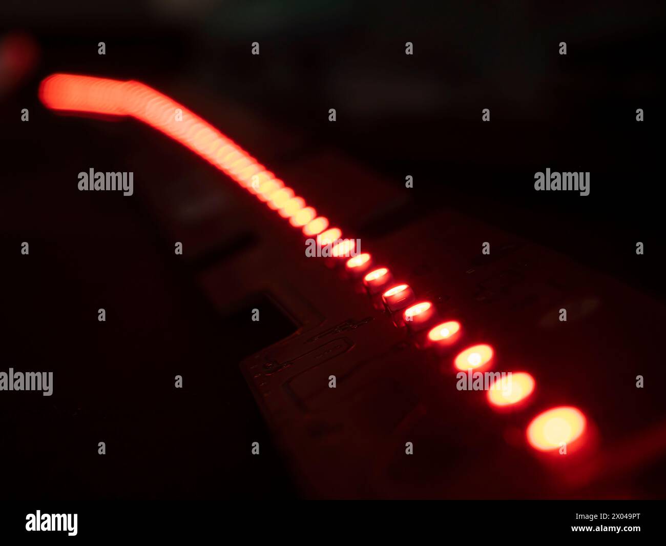 Primo piano della striscia LED rossa su sfondo nero con profondità di campo ridotta Foto Stock