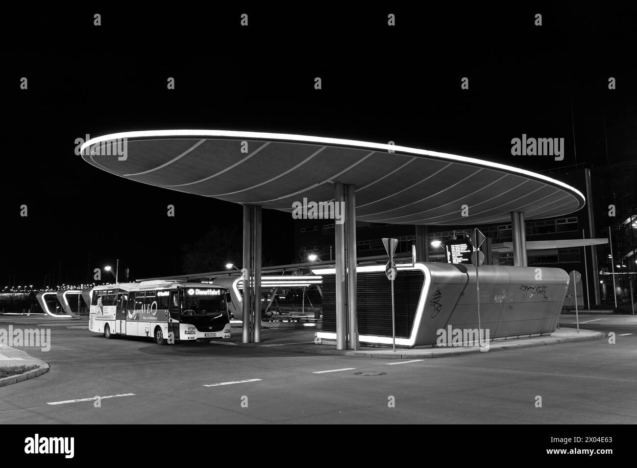 Moderna stazione centrale degli autobus illuminata di notte ad Halle in un quadro in bianco e nero Foto Stock