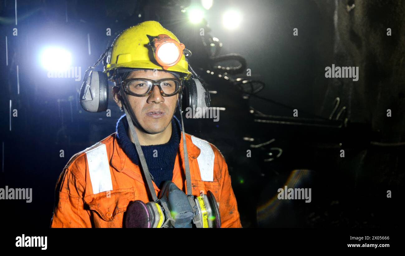 Cerro de Pasco, Perù - 14 luglio 2017 : Ritratto di un minatore concentrato che indossa un faro e un equipaggiamento di sicurezza in una miniera sotterranea scarsamente illuminata Foto Stock