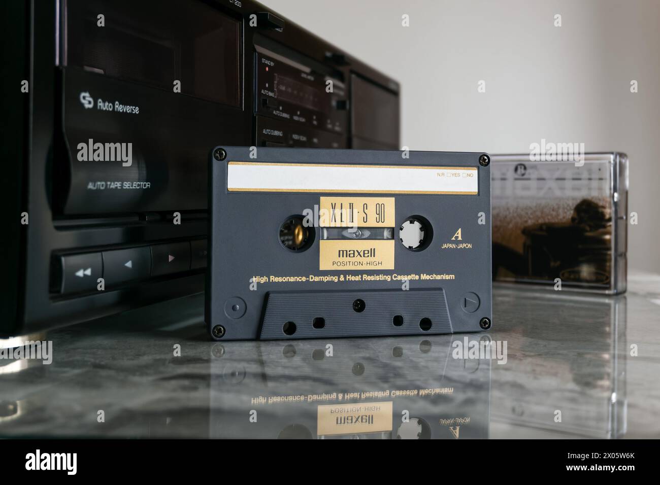 Cassetta audio Maxell XL II - S 90 davanti al piano portacassetta su un piano in marmo lucido con riflesso Foto Stock