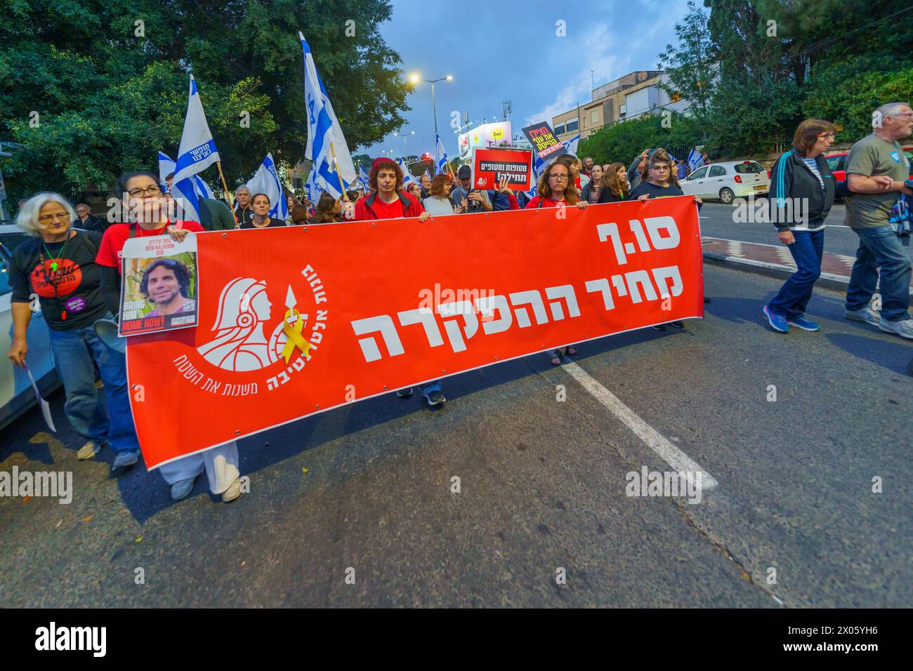 Haifa, Israele - 6 aprile 2024: La gente partecipa a una marcia di protesta, con vari segni e bandiere, contro il governo, che chiede nuove elezioni. Foto Stock