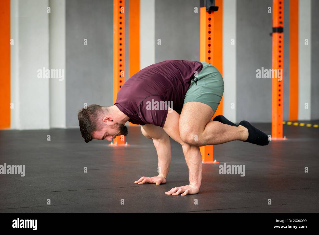 Vista laterale dell'esercizio fisico fisico fisico delle rane calisteniche maschile sul pavimento nella moderna palestra Foto Stock