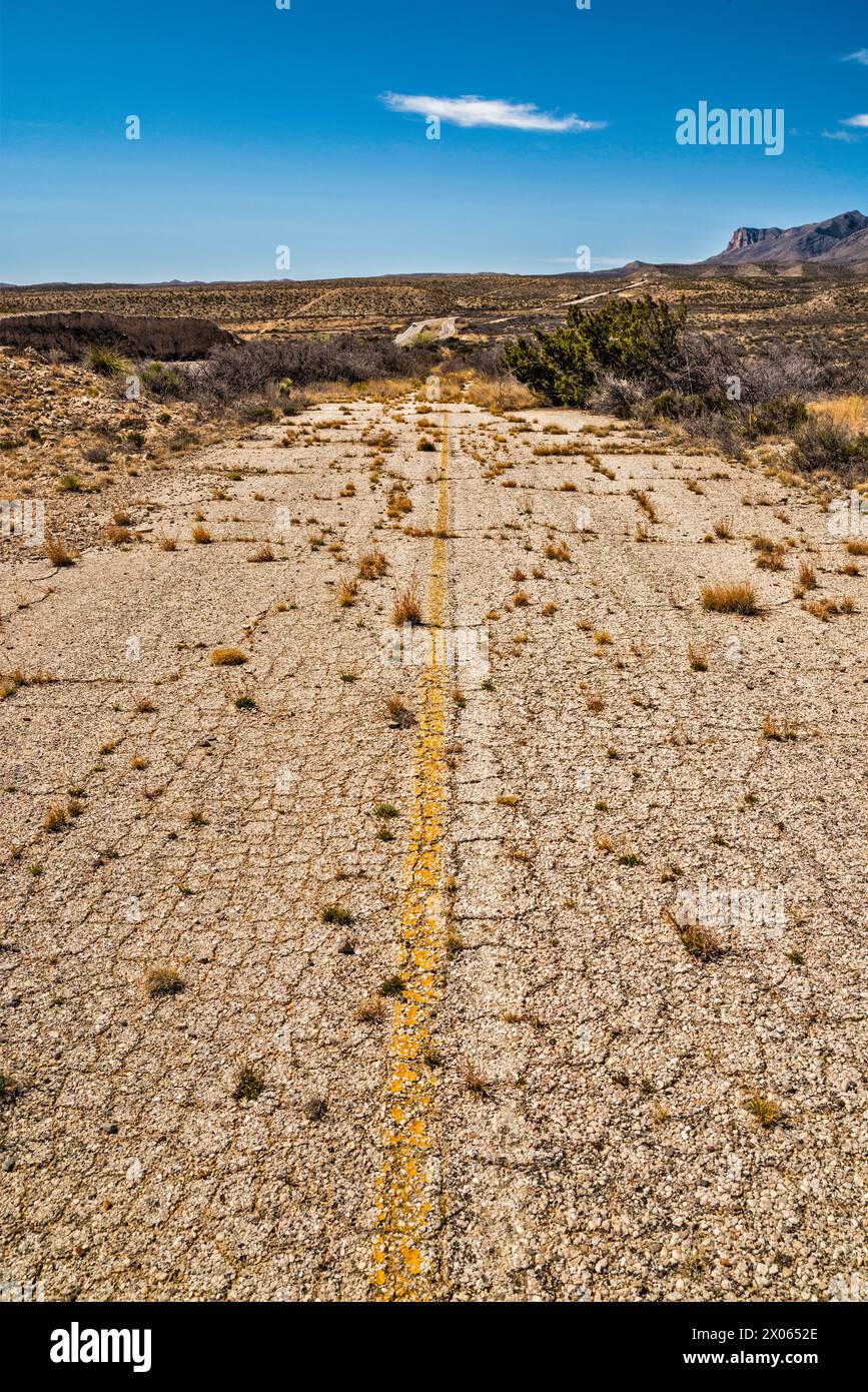Sezione abbandonata dell'autostrada US-180, US-62 con overgrowth, Guadalupe Mountains in lontananza, Texas, USA Foto Stock