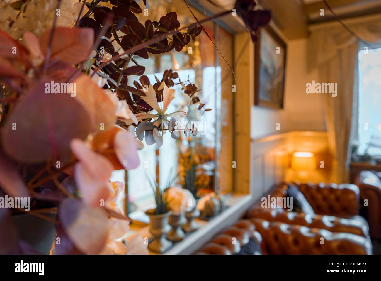 Eleganti arredi interni con piante viola, divano in pelle e lampada in un'atmosfera accogliente. Foto Stock