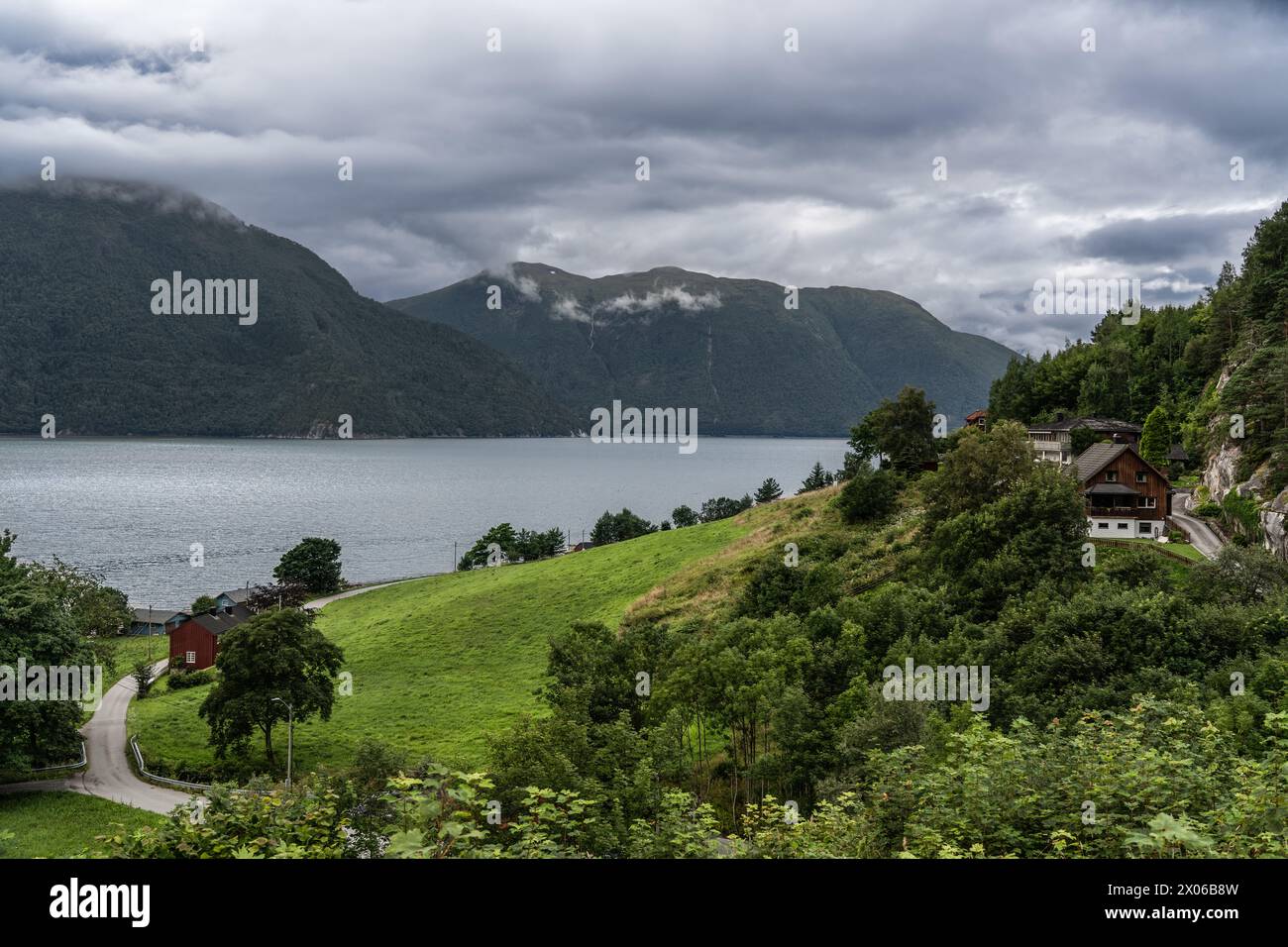 Cieli tempestosi su Tingvollfjorden vicino al villaggio di Ålvundeid. Il clima sovrasta il fiordo con case rurali norvegesi immerse nel verde lussureggiante Foto Stock