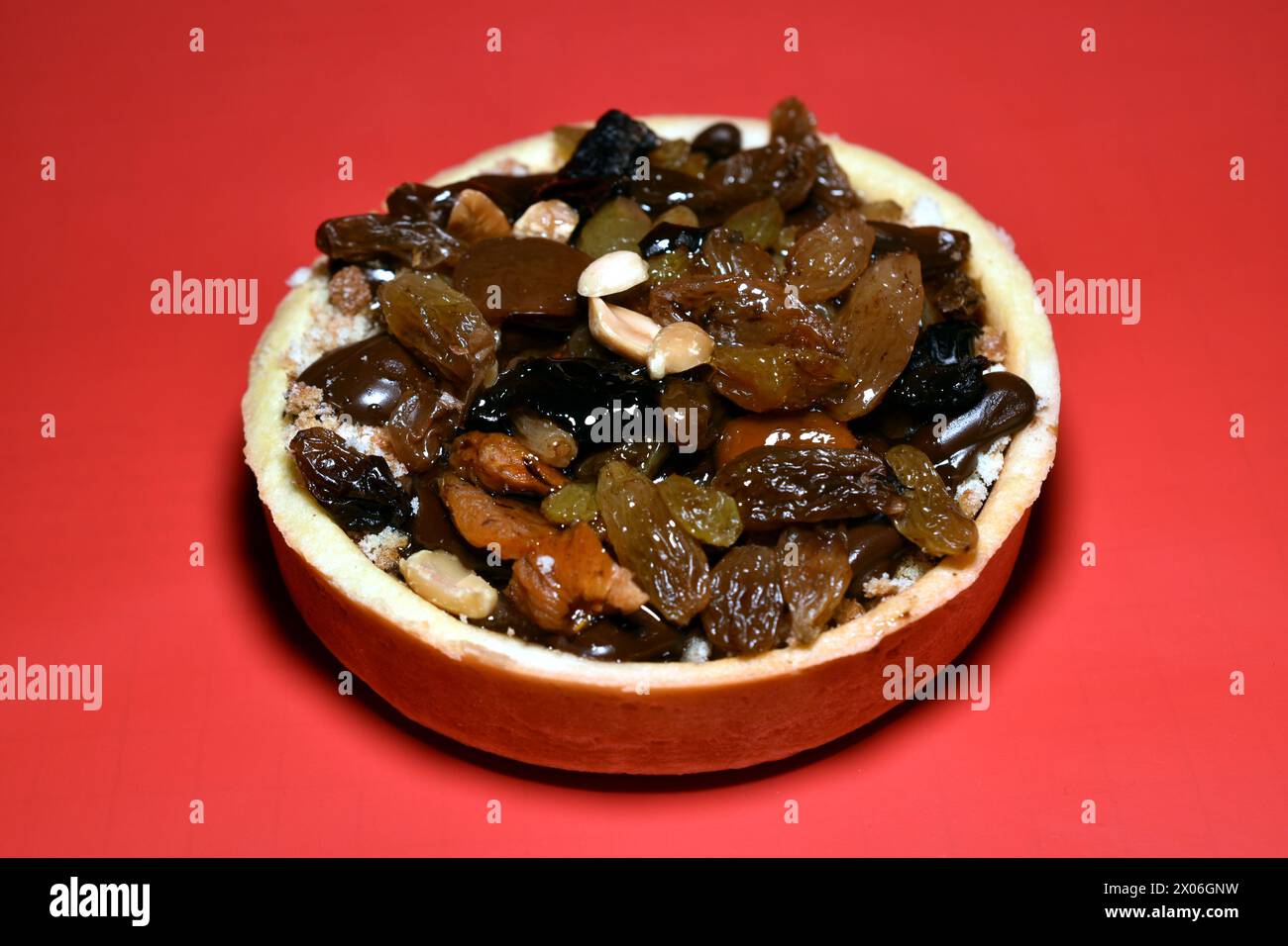 Torta rotonda composta da cesto, formaggio fresco, noci e uvetta su sfondo rosso, primo piano. Foto Stock