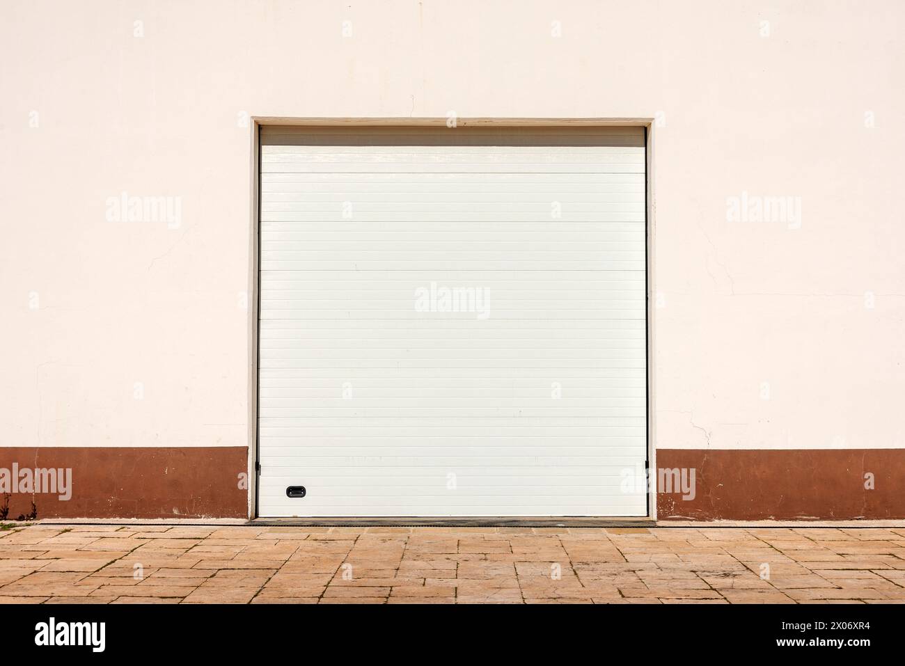 Porta a rulli bianca. Serranda metallica a rullo davanti alla parete color crema. Foto Stock