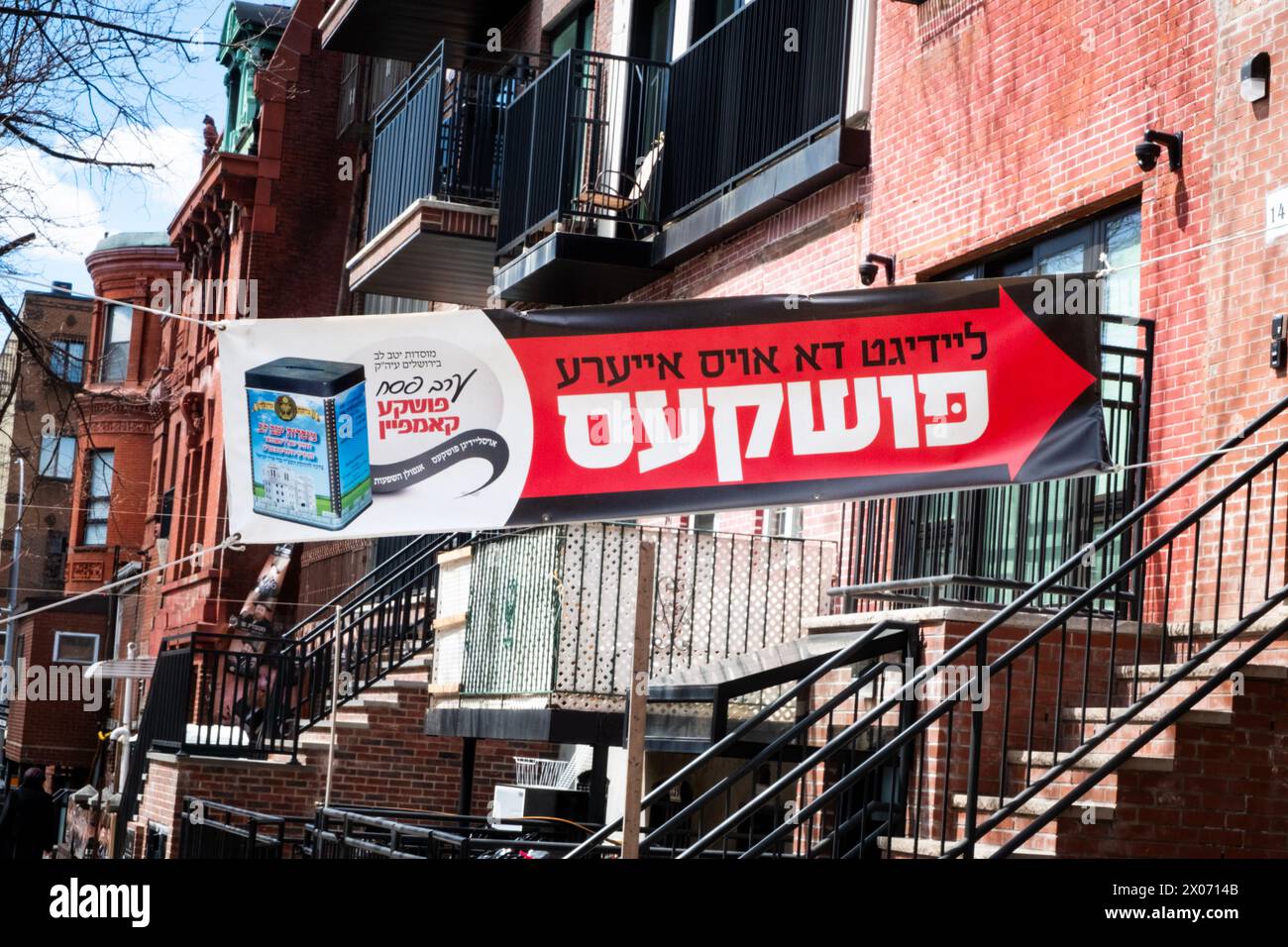 Una grande bandiera che incoraggia le persone a donare carità per Satmar yeshivas in Israele, mettendo monete in un pushka. Su Rodney St a Brooklyn, New York. Foto Stock