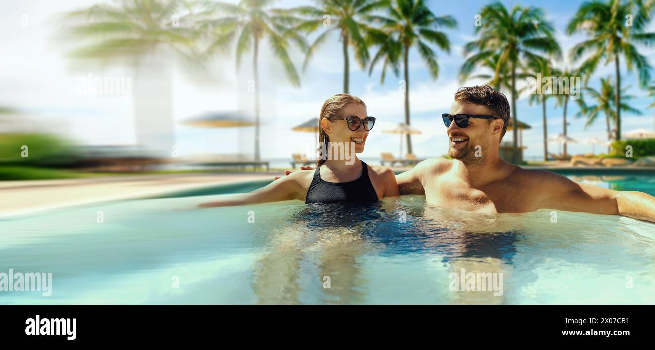 coppia che si rilassa nella vasca idromassaggio presso la piscina del resort tropicale. banner con spazio di copia Foto Stock